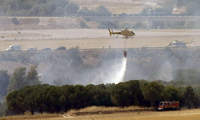 En el aeropuerto de Madrid, helicópteros y camiones de bombaeros arrojaron agua sobre el avión, que se detuvo en una zona arbolada al final de la pista de la Terminal 4. AP 