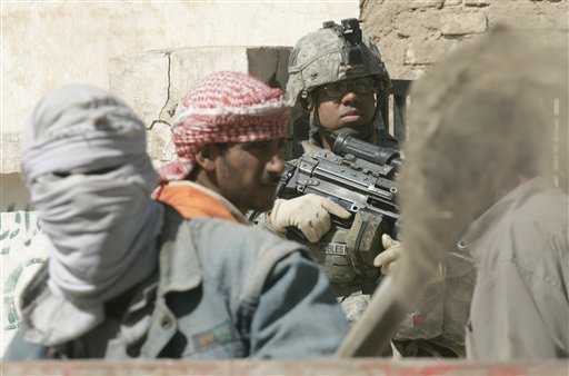 Joshua Robles, de Columbus, Georgia, vigila mientras obreros iraquíes trabajan para despejar una calle en Salman Pak, a 45 kilómetros al sur de Bagdad. PETROS GIANNAKOURIS / AP 