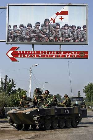 Un transporte APC ruso pasa bajo un cartel del Ejército georgiano en Senaki. (Foto: AFP)