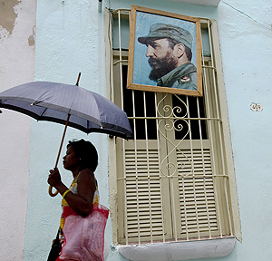  Una cubana camina por las calles de Santiago, donde aún pueden verse fotos de Fidel Castro colgadas en las puertas de las casas.