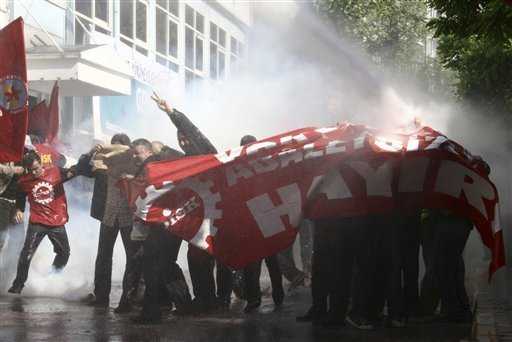 Trabajadores turcos usan una pancarta que reza ’No a la pobreza y la injusticia’ para protegerse de las ráfagas de agua con que la policía de Estanbul disvolvió su manifestación. Emrah Dalkaya / AP 