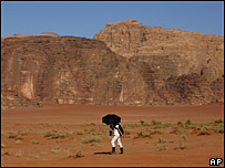 Una turista con un paraguas en el desierto de Wadi Rum en Jordania