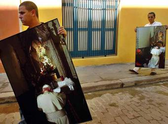 Dos obreros cubanos transportan fotografías, tomadas hace diez años, del fallecido papa Juan Pablo II, en La Habana Vieja