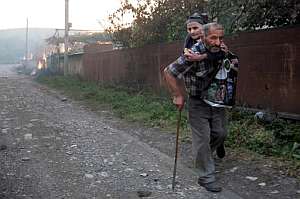 Una pareja de ancianos huye de una casa en llamas atacada por las milicias de Osetia del Sur en una aldea georgiana. (Foto: EFE)